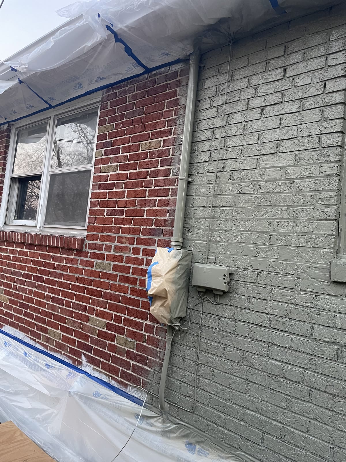 Mid-project exterior brick painting transitioning red brick to gray