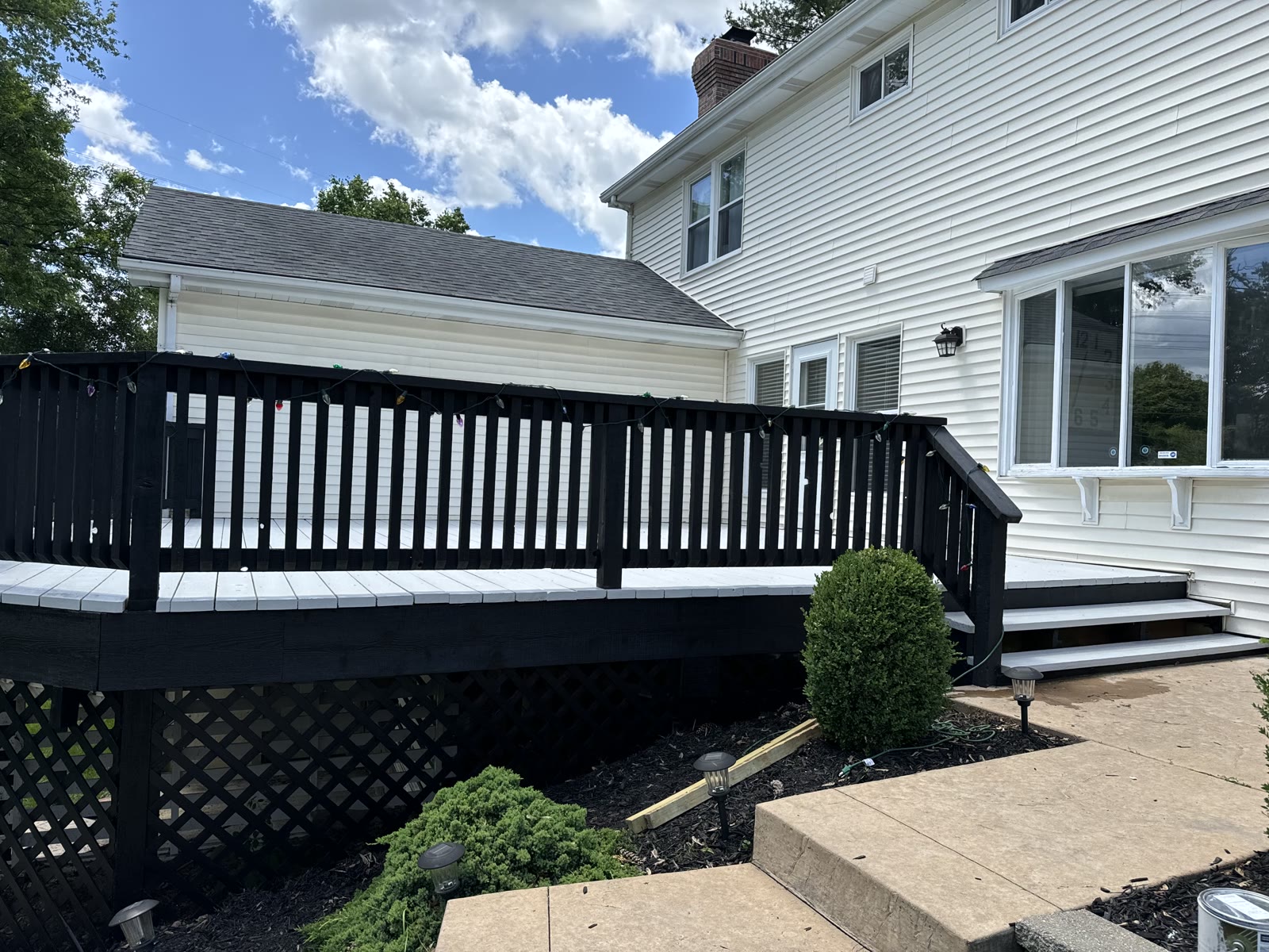 Refinished black wood deck with white-painted top boards behind a two-story home