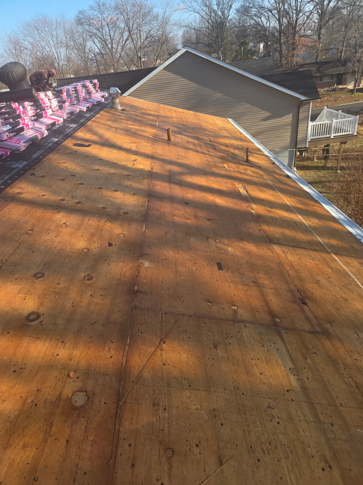 Exposed roof decking with shingle bundles staged at the peak
