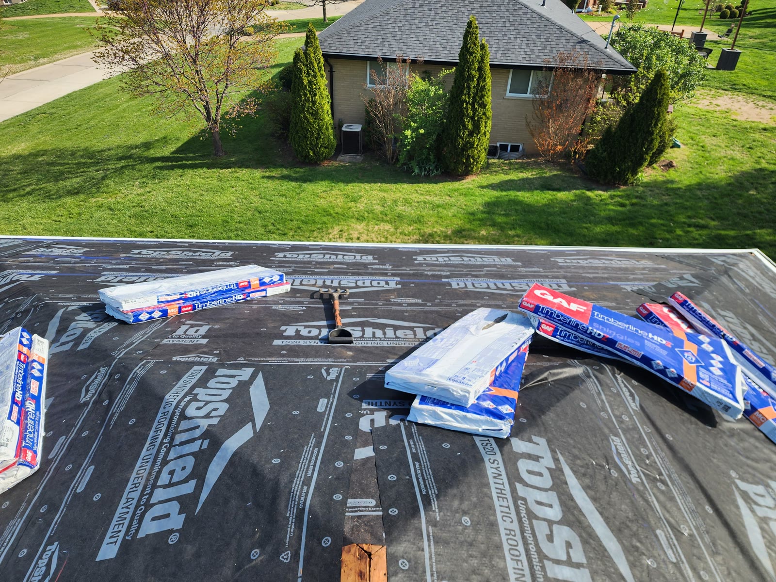 Synthetic roofing underlayment with shingle bundles staged for install