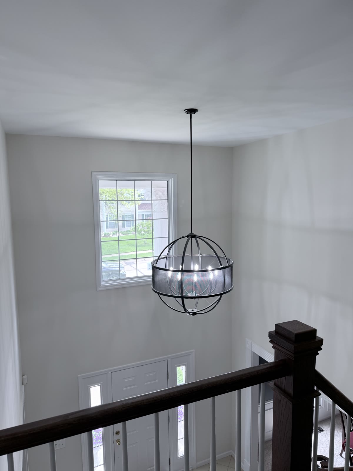 Freshly finished two-story entryway with drywall, paint, and modern globe pendant light