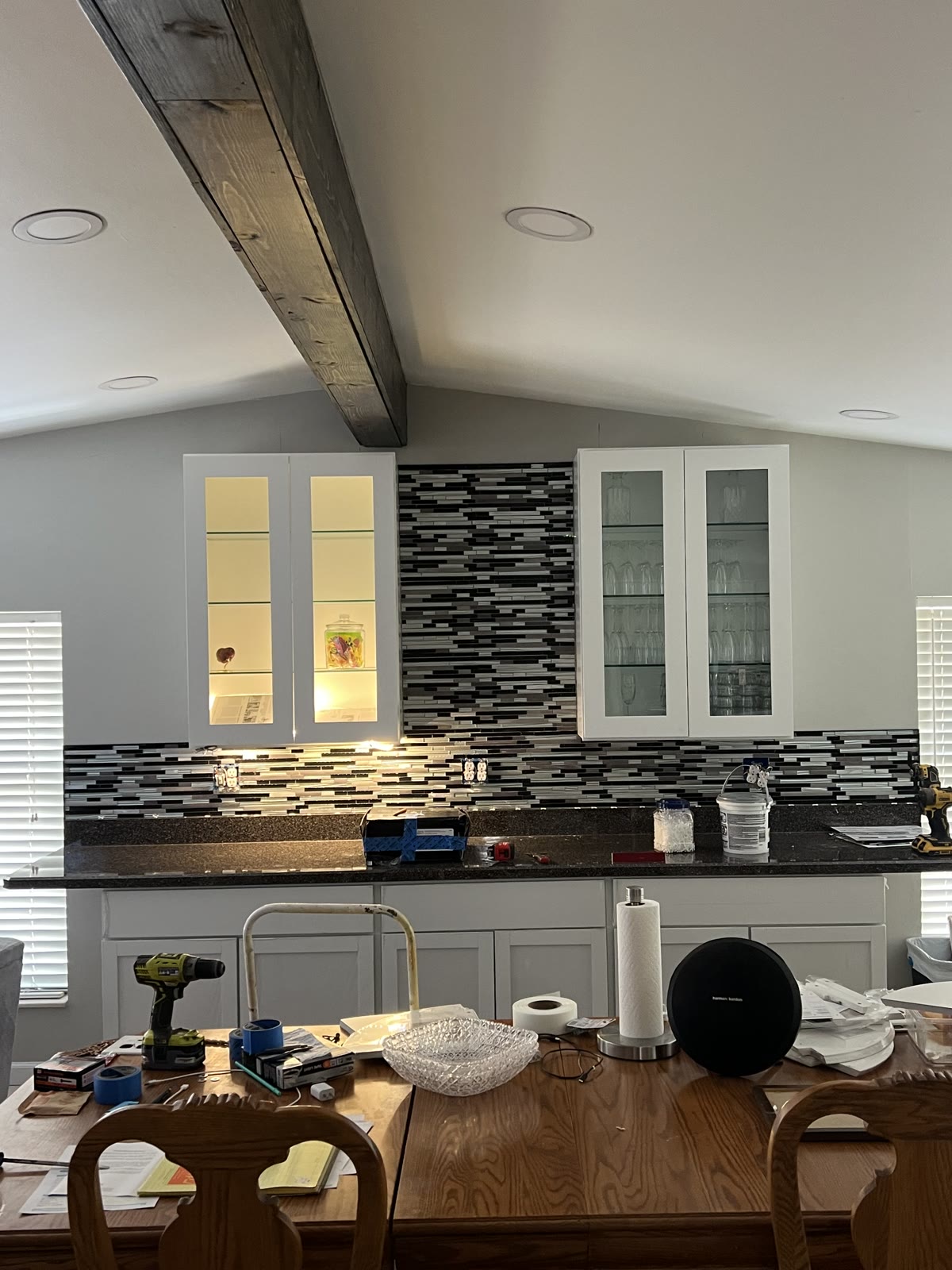 Completed kitchen remodel with mosaic tile backsplash, granite tops, and exposed wood beam