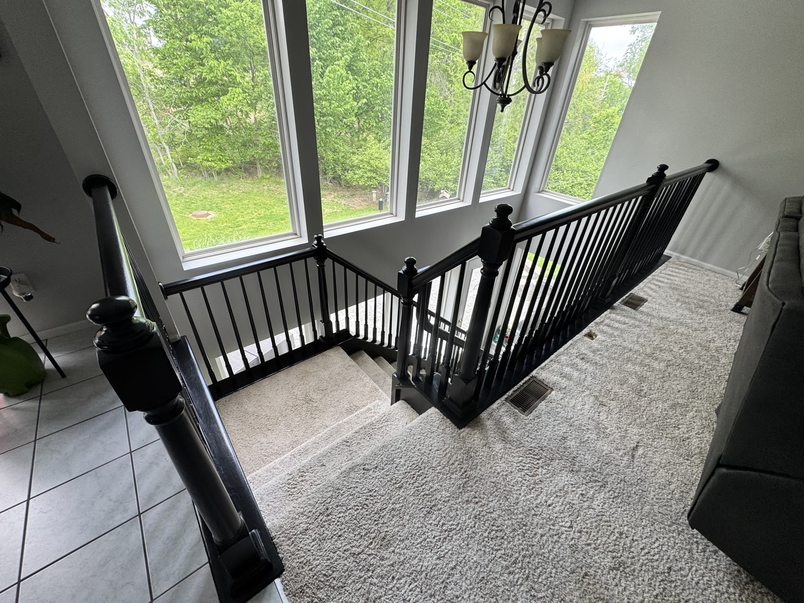 Completed staircase remodel with black iron railing, carpet, and large windows